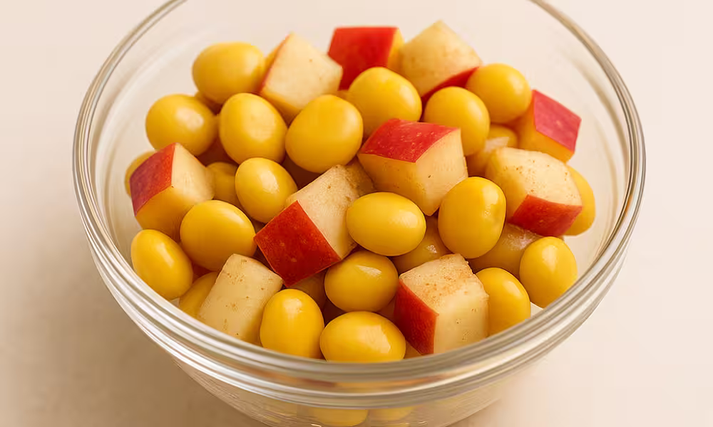 Back-to-school high-protein breakfast cup with lupini beans, diced red apple, and a dusting of cinnamon, served in a clear glass bowl.