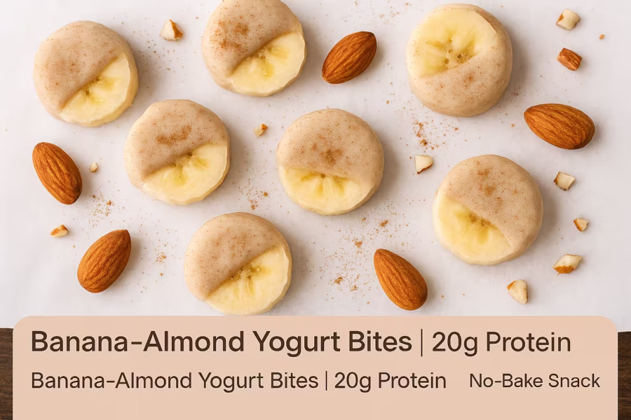 A bright overhead flat-lay food photo of Banana–Almond Yogurt Bites on white parchment paper. Frozen banana slices are dipped in a creamy yogurt and almond butter coating, with a few scattered almond pieces and a light dusting of cinnamon for texture. The color theme is soft beige, yellow, and white, giving a clean and fresh look. Overlay text in the corner reads: “Banana–Almond Yogurt Bites | 20g Protein | No-Bake Snack.”