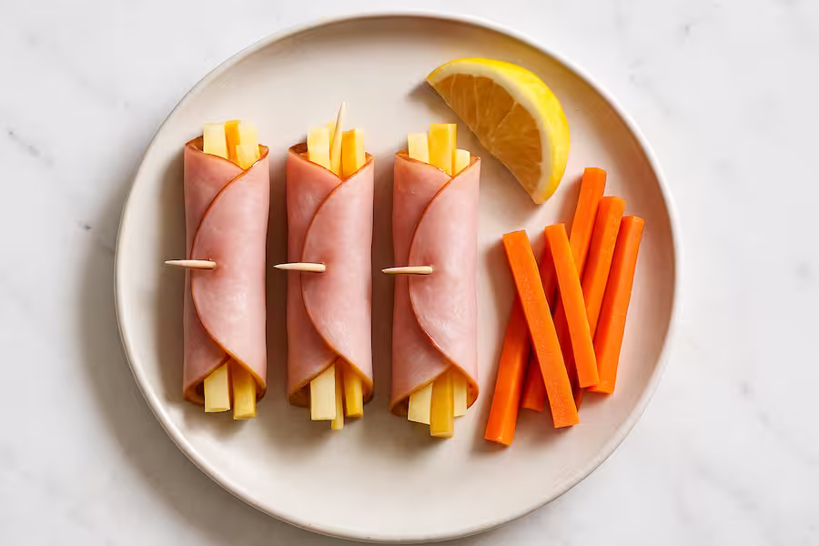 Ham roll-ups filled with sharp cheddar and apple sticks, served with carrot side — quick high-protein lunch